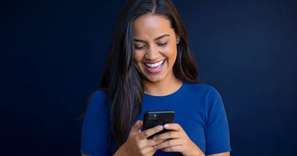 Mulher rindo ao ver meme no celular, representando marketing de conteúdo no Instagram